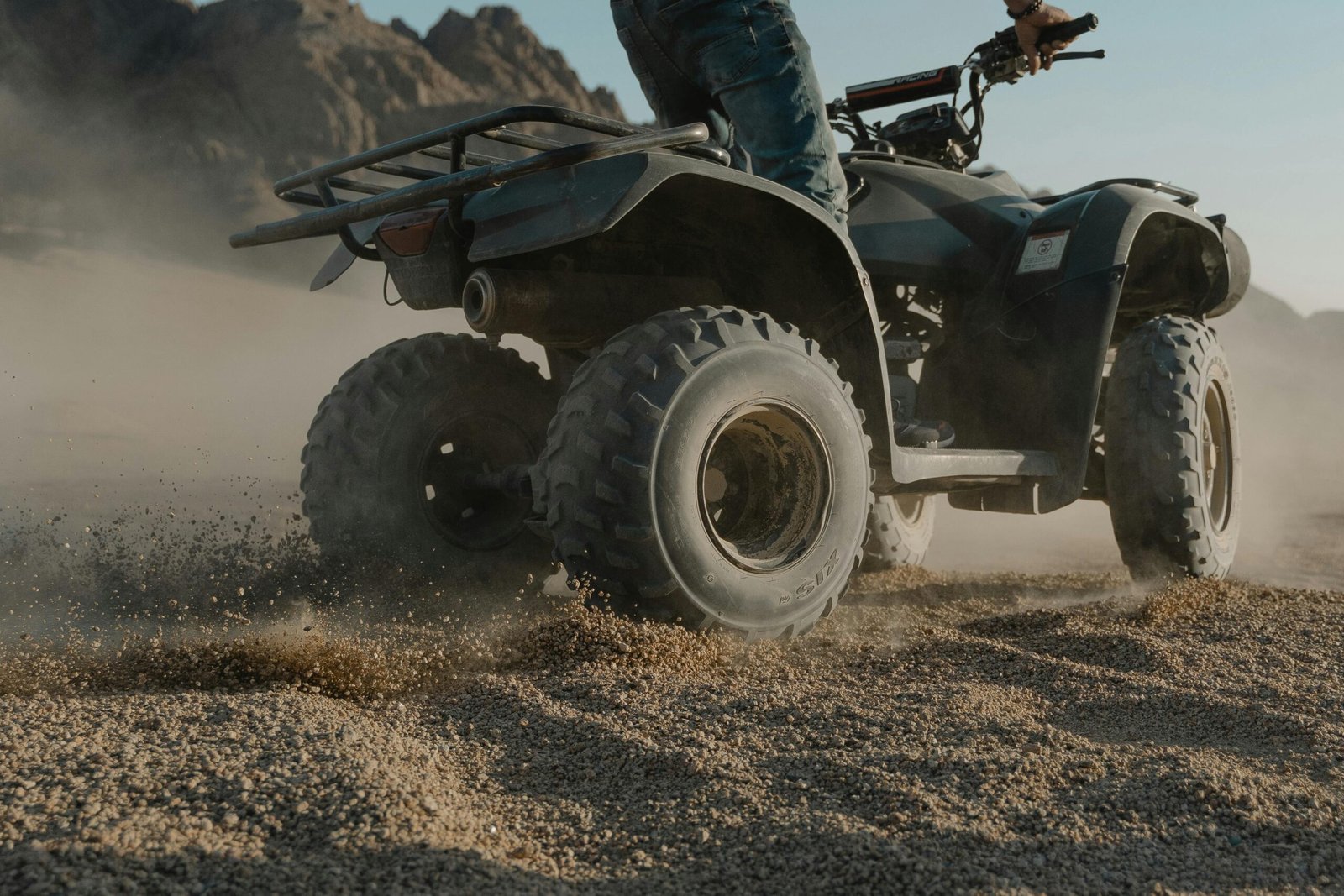 Thrilling ATV ride through desert sand at daytime, showcasing power and adventure in rugged terrain.